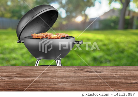 summer time in backyard garden with grill BBQ, wooden table, blurred background summer time in backyard garden with grill BBQ, wooden table, blurred background 141125097