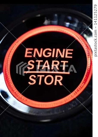 A car's engine start switch that lights up red. 141125279