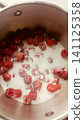Top-down view of fresh red raspberries and white granulated sugar inside a stainless steel cooking pot, ready for making jam. 141125358