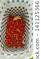 Top-down view inside a checkered woven basket filled with freshly picked red strawberries and one wild mushroom. 141125366