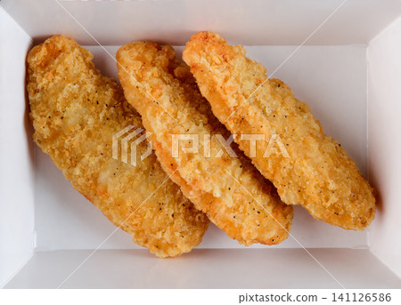 Freshly baked crispy chicken strip in white paper takeout container top view extreme close up flat lay delicious savory american junk food snack Freshly baked crispy chicken strip in white paper takeout container top view extreme close up flat lay delicious savory american junk food snack 141126586