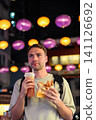 Handsome 30 years old Russian man tourist holding traditional bubble waffle and iced lemon tea at illuminated Temple Street Night Market in Hong Kong 141126692
