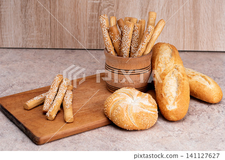 French baguettes. Fresh crispbread. Bread background. Different breed on wooden background. French baguettes. Fresh crispbread. Bread background. Different breed on wooden background. 141127627