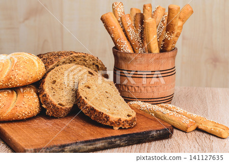 French baguettes. Fresh crispbread. Bread background. Different breed on wooden background. French baguettes. Fresh crispbread. Bread background. Different breed on wooden background. 141127635