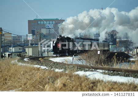SL 冬季沼澤地號列車強勁地穿過釧路的冬日街道，伴隨著滾滾白煙。 141127831