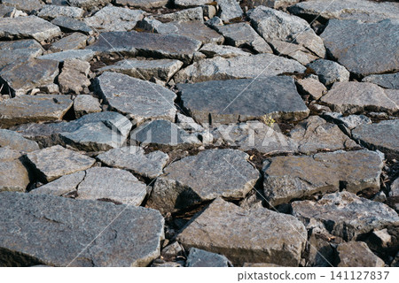Close-up of natural granite rocks forming a rugged stone texture. Abstract rocky background with gray stones, suitable for nature, geology, construction, and outdoor themes. Close-up of natural granite rocks forming a rugged stone texture. Abstract rocky background with gray stones, suitable for nature, geology, construction, and outdoor themes. 141127837