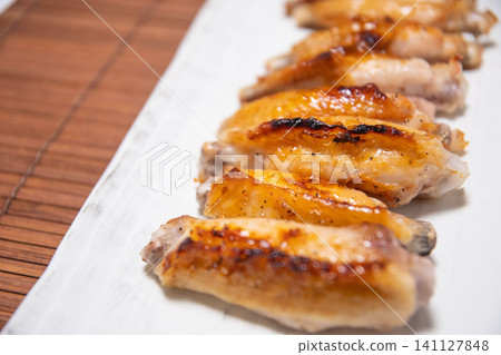 Grilled chicken wings served on a white square plate Grilled chicken wings served on a white square plate 141127848