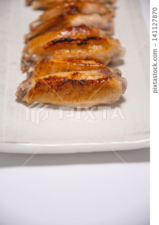 Grilled chicken wings served on a white square plate Grilled chicken wings served on a white square plate 141127870