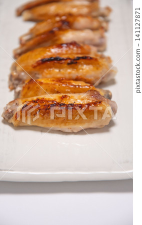 Grilled chicken wings served on a white square plate Grilled chicken wings served on a white square plate 141127871