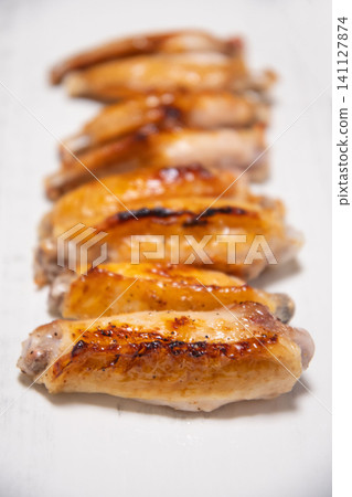 Grilled chicken wings served on a white square plate 141127874