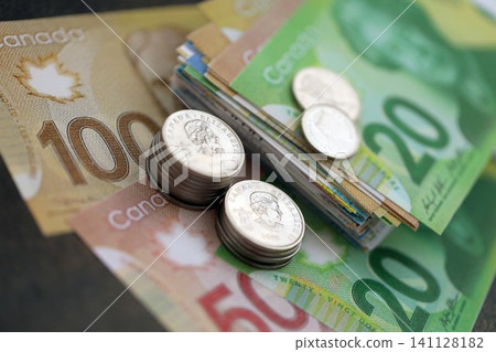 Canadian dollar money bills and cent coins pile on table. Canada coins on banknotes of CAD currency close up. Concept of business, taxes and banking in Canada Canadian dollar money bills and cent coins pile on table. Canada coins on banknotes of CAD currency close up. Concept of business, taxes and banking in Canada 141128182