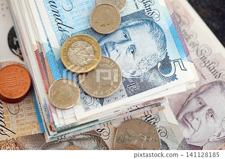 British pound money bills and penny coins pile on table. United Kingdom coins on banknotes of GBP currency close up. Concept of business, taxes and banking in United Kingdom British pound money bills and penny coins pile on table. United Kingdom coins on banknotes of GBP currency close up. Concept of business, taxes and banking in United Kingdom 141128185