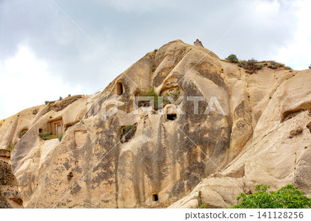Rock formations with ancient cave dwellings in a mountainous area at a cloudy time of day 141128256