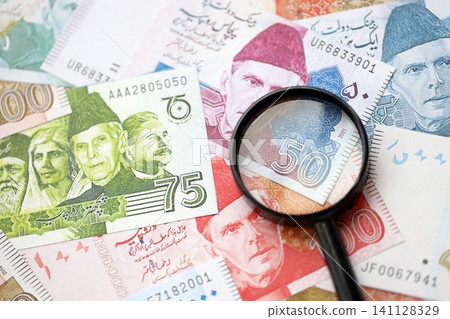 Pakistan rupees banknotes and magnifying glass. The current Pakistan money bills with loupe Pakistan rupees banknotes and magnifying glass. The current Pakistan money bills with loupe 141128329