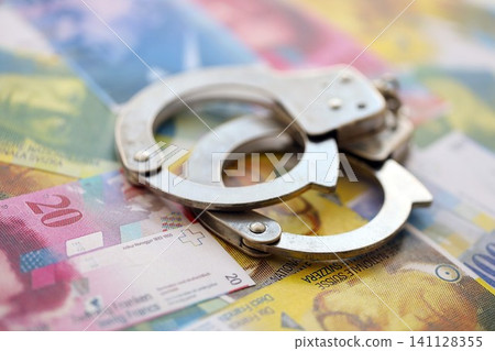 Swiss franc banknotes and handcuffs. The current francs money bills and cuffs lies on table 141128355
