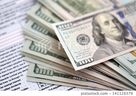 Big amount of United States hundred dollar bills on table with tax return form close up Big amount of United States hundred dollar bills on table with tax return form close up 141128379