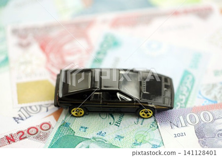 Nigerian naira currency money bills and toy car. The concept of car ownership Nigerian naira currency money bills and toy car. The concept of car ownership 141128401