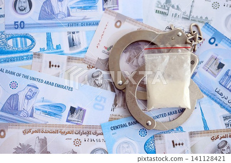 United Arab Emirates dirham currency money bills and cocaine pack with handcuffs. The concept of drug crimes United Arab Emirates dirham currency money bills and cocaine pack with handcuffs. The concept of drug crimes 141128421
