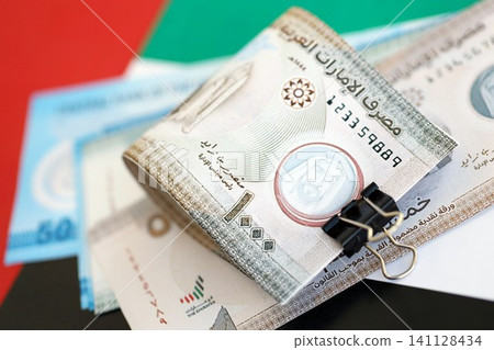 United Arab Emirates dirham currency money bills lies on flag. The concept of business and investment United Arab Emirates dirham currency money bills lies on flag. The concept of business and investment 141128434