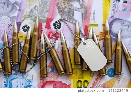 Philippines peso currency money bills and rifle bullets with dogtag. The concept of warfare and army service Philippines peso currency money bills and rifle bullets with dogtag. The concept of warfare and army service 141128449