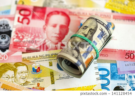 Philippines peso currency money bills and bunch of us dollar banknotes. The concept of economics and currency exchange Philippines peso currency money bills and bunch of us dollar banknotes. The concept of economics and currency exchange 141128454