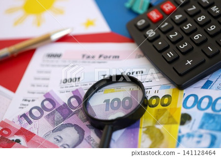 Philippines peso money bills and calculator with tax form on flag. Taxation and accounting concept Philippines peso money bills and calculator with tax form on flag. Taxation and accounting concept 141128464