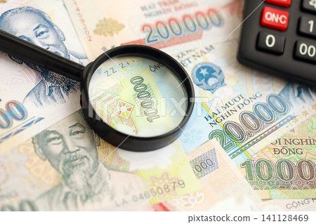 Vietnamese dong currency money bills and calculator with magnifying glass. The concept of taxation and money count Vietnamese dong currency money bills and calculator with magnifying glass. The concept of taxation and money count 141128469