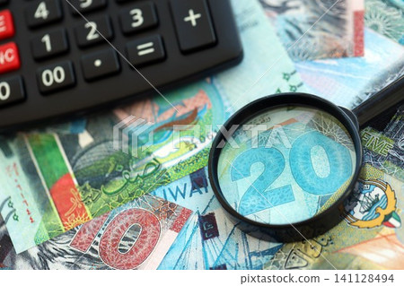 Kuwaiti dinar currency money bills and calculator with magnifying glass. The concept of taxation and money count Kuwaiti dinar currency money bills and calculator with magnifying glass. The concept of taxation and money count 141128494