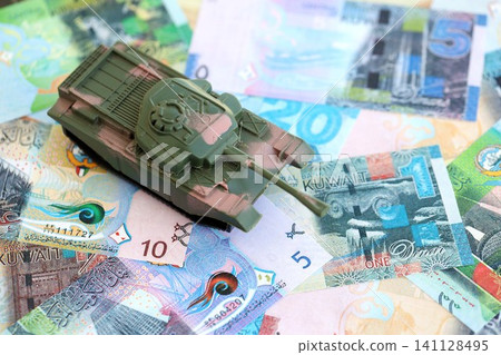 Kuwaiti dinar currency money bills and toy tank. The concept of army funds and weapons sales Kuwaiti dinar currency money bills and toy tank. The concept of army funds and weapons sales 141128495
