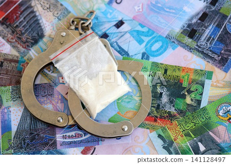 Kuwaiti dinar currency money bills and cocaine pack with handcuffs. The concept of drug crimes 141128497