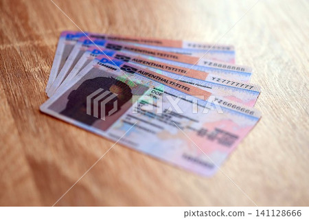 German Permanent resident specimen cards lies on wooden table. Aufenthaltstitel German Permanent resident specimen cards lies on wooden table. Aufenthaltstitel 141128666
