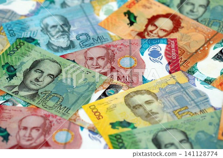 Costa Rican new colon money bills pile on table. Costa Rica banknotes of CRC currency close up Costa Rican new colon money bills pile on table. Costa Rica banknotes of CRC currency close up 141128774