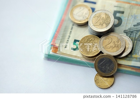 Eurozone euro money bills and cent coins pile on table. Eurozone coins on banknotes of EUR currency Eurozone euro money bills and cent coins pile on table. Eurozone coins on banknotes of EUR currency 141128786