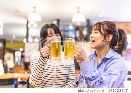 Two smiling women toast with beer. Two smiling women toast with beer. 141128837