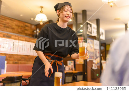 A woman serving beer to customers 141128965