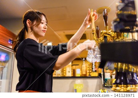 一名女子正在從啤酒龍頭倒啤酒。 141128971