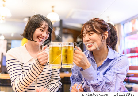 A woman toasting with beer with a smile A woman toasting with beer with a smile 141128983
