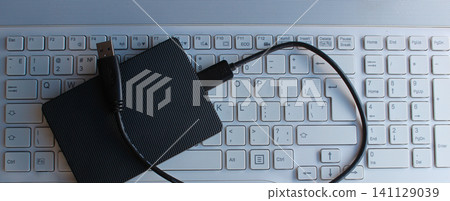 Panoramic photo of unconnected HDD with a USB cable lies on the laptop keyboard Panoramic photo of unconnected HDD with a USB cable lies on the laptop keyboard 141129039