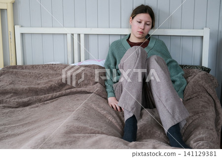 Teenager girl with depression sitting alone in the home room. Upset teenage girl suffering from stress for education. Crying for fail or bullying. Sad, anxiety. Mental health in adolescence concept. Teenager girl with depression sitting alone in the home room. Upset teenage girl suffering from stress for education. Crying for fail or bullying. Sad, anxiety. Mental health in adolescence concept. 141129381