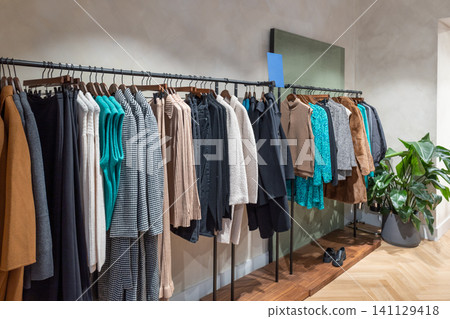 Boutique interior with hanging garments and a decorative wall shelf Boutique interior with hanging garments and a decorative wall shelf 141129418