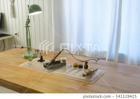 Soldering iron and tools on the desktop. Solderer workplace. Engineer's desk. STEM education. DIY school science and technology project. Hobbies are electronics. Hardware, technician and technology. 141129425