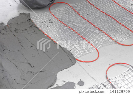 Electric Heating Mat Installing in the Tile Adhesive. Underfloor Dual Core Fiberglass Mesh Mat. Warm Floor Heating System. Warming. Worker Applying Concrete Mortar for Warm Floor. Renovation work. 4K 141129709