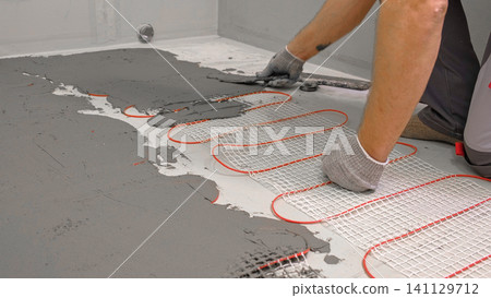 Electric Heating Mat Installing in the Tile Adhesive. Underfloor Dual Core Fiberglass Mesh Mat. Warm Floor Heating System. Warming. Worker Applying Concrete Mortar for Warm Floor. Renovation work. 4K Electric Heating Mat Installing in the Tile Adhesive. Underfloor Dual Core Fiberglass Mesh Mat. Warm Floor Heating System. Warming. Worker Applying Concrete Mortar for Warm Floor. Renovation work. 4K 141129712