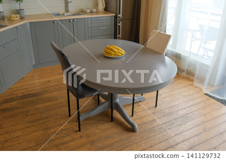 Dining room interior. Gray oval dining table, wood flooring, grey cabinets. Interior design of stylish kitchen with family table, modern chairs. Wooden floor. White wall. Template. New Luxury Home. Dining room interior. Gray oval dining table, wood flooring, grey cabinets. Interior design of stylish kitchen with family table, modern chairs. Wooden floor. White wall. Template. New Luxury Home. 141129732