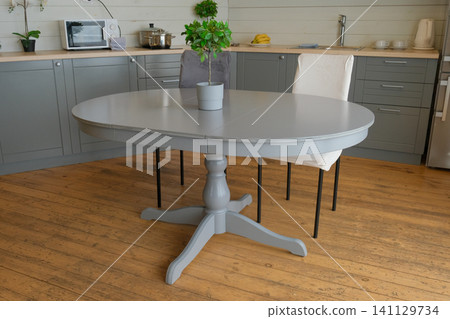 Dining room interior. Gray oval dining table, wood flooring, grey cabinets. Interior design of stylish kitchen with family table, modern chairs. Wooden floor. White wall. Template. New Luxury Home. Dining room interior. Gray oval dining table, wood flooring, grey cabinets. Interior design of stylish kitchen with family table, modern chairs. Wooden floor. White wall. Template. New Luxury Home. 141129734