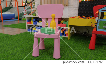 Comfortable vivid multicolored kids playroom or kindergarten nursery interior design with kid toys, play space. Bright and spacious colorful game room for children with plastic educational blocks toys Comfortable vivid multicolored kids playroom or kindergarten nursery interior design with kid toys, play space. Bright and spacious colorful game room for children with plastic educational blocks toys 141129765