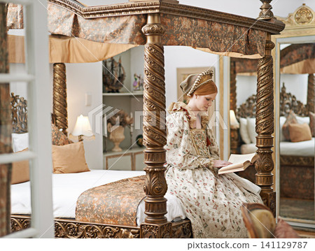 Woman, queen and book with reading for renaissance, royalty aesthetic and confidence on palace bed. Monarch, wealthy person and elegant dress for cosplay, regal and medieval knowledge in the castle 141129787