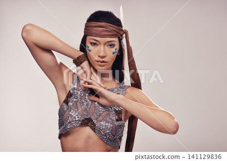 Portrait, girl and Native American culture in studio with warrior makeup, confidence and tribe style. Indigenous fashion, face paint or woman in First Nations clothes on white background with feather Portrait, girl and Native American culture in studio with warrior makeup, confidence and tribe style. Indigenous fashion, face paint or woman in First Nations clothes on white background with feather 141129836