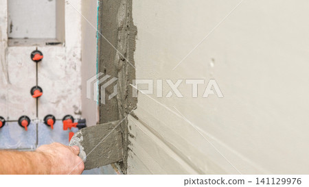 Worker Laying Ceramic Tiles on the Wall. Repairman Placing White Gray Square Tiles, Applying Adhesive. Builder Installing Tile Using Leveler, Tile Leveling Clips. Tiling. Finishing Repair Work. 4K Worker Laying Ceramic Tiles on the Wall. Repairman Placing White Gray Square Tiles, Applying Adhesive. Builder Installing Tile Using Leveler, Tile Leveling Clips. Tiling. Finishing Repair Work. 4K 141129976