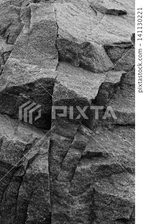 Pattern of ledges on raw surface of wild granite with quartz inclusions. Dark gray granite texture vertical image 141130221